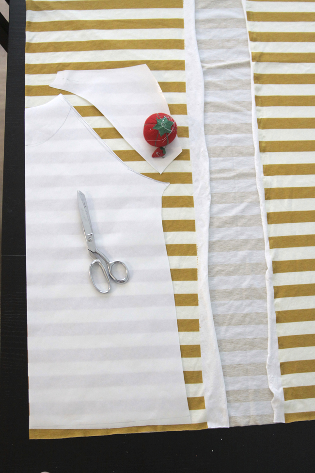 Cutting out raglan t-shirt pattern on yellow and white striped fabric