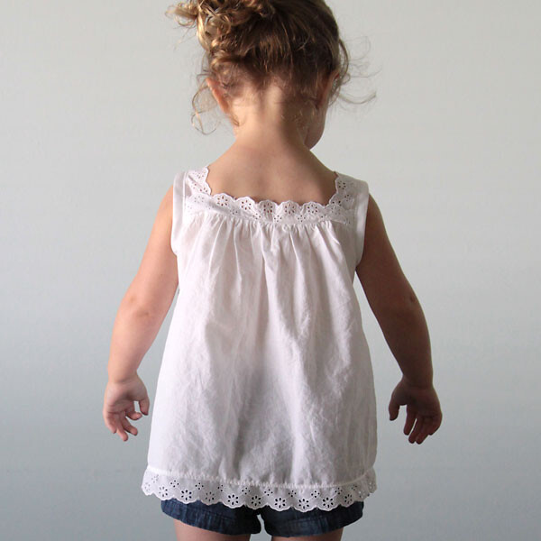 A young girl in a white blouse with lace at the hem, neckline, and straps