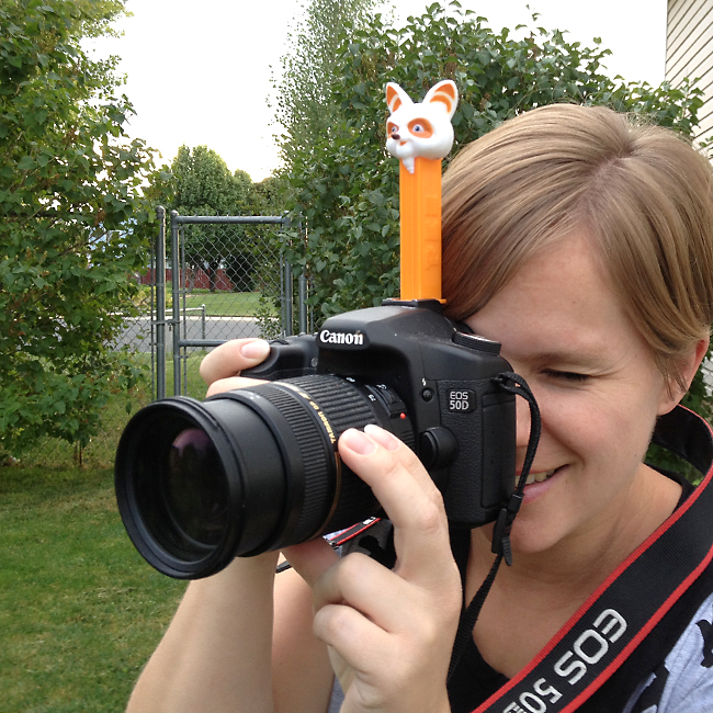 A woman holding a camera with a pez dispenser attached on top