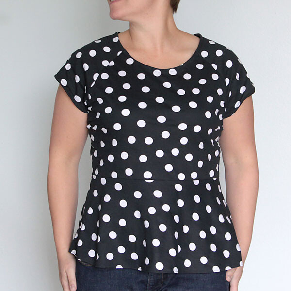 A woman wearing a short sleeve black peplum top with white polka dots