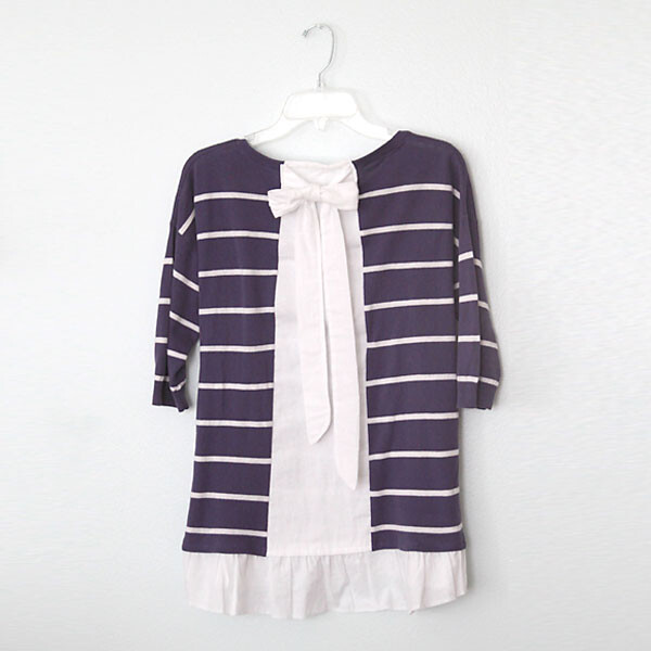 A purple striped sweater with white ruffled hem and bow in the back