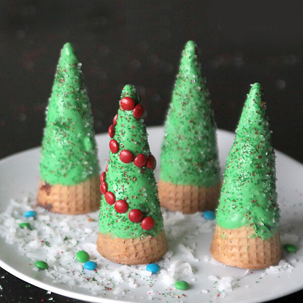 ice cream cones turned upside down and decorated with green frosting and candy to look like Christmas trees