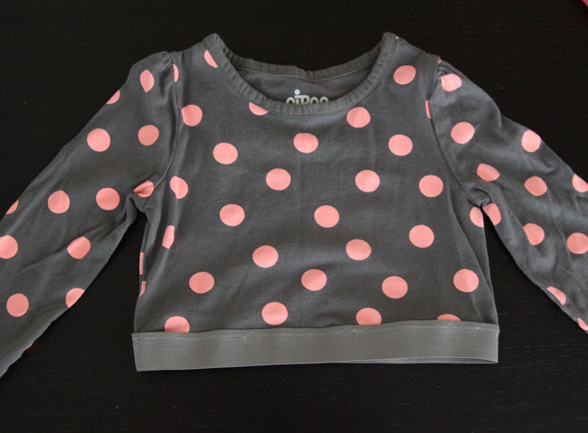 A long sleeve polka dot t-shirt cut off at the waist with elastic sewn around the bottom