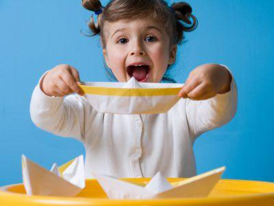 Girl holding a folded paper boat