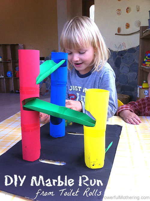 A girl playing with a track made from cardboard tubes