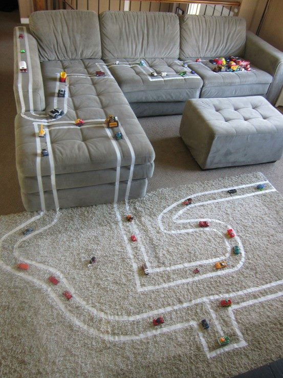 A living room with a car track made out of masking tape all over the couch and carpet