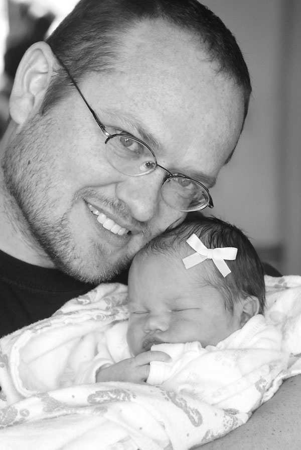 black and white photo of a dad snuggling his newborn baby