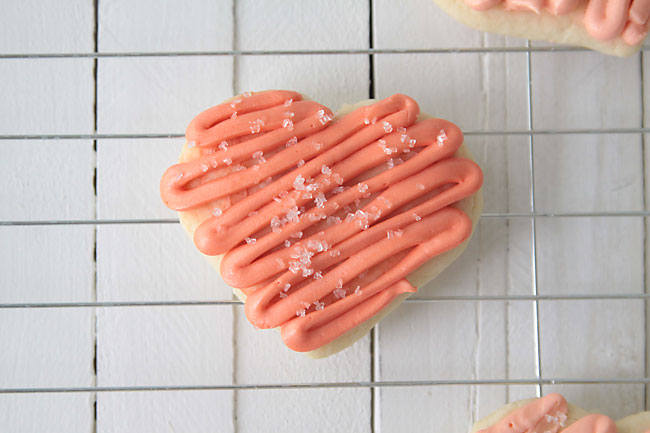 Heart shaped sugar cookie with pink frosting and decorative sugar