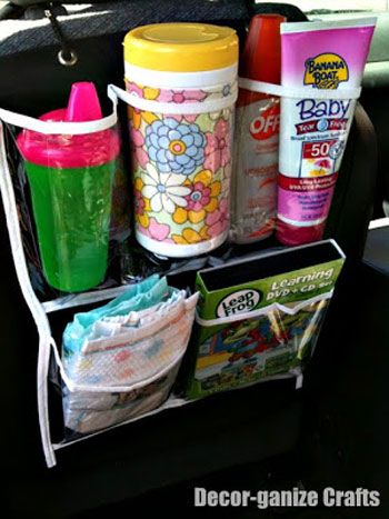 A shoe organizer on the back of a car seat with a sippy cup, wipes, sunblock, and diapers in it