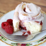 A raspberry sweet roll with cream cheese frosting on a plate