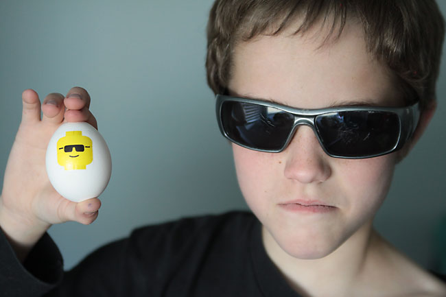 a boy wearing sunglasses holding an Easter egg with a lego minifig on it