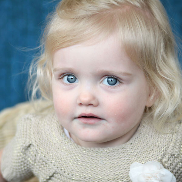 A close up of a baby girl with a blue background