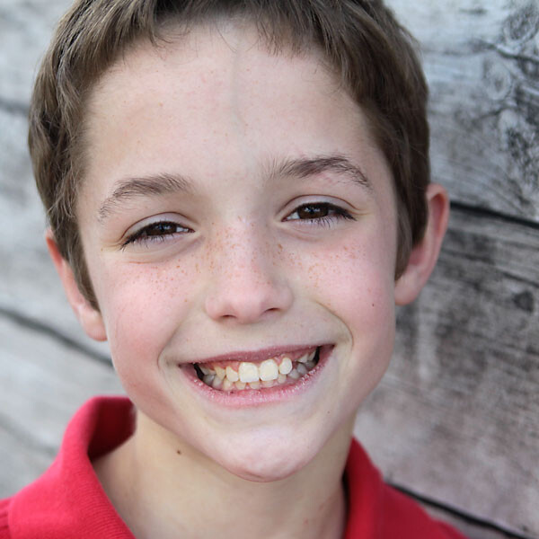 A person posing for the camera next to a wood plank wall