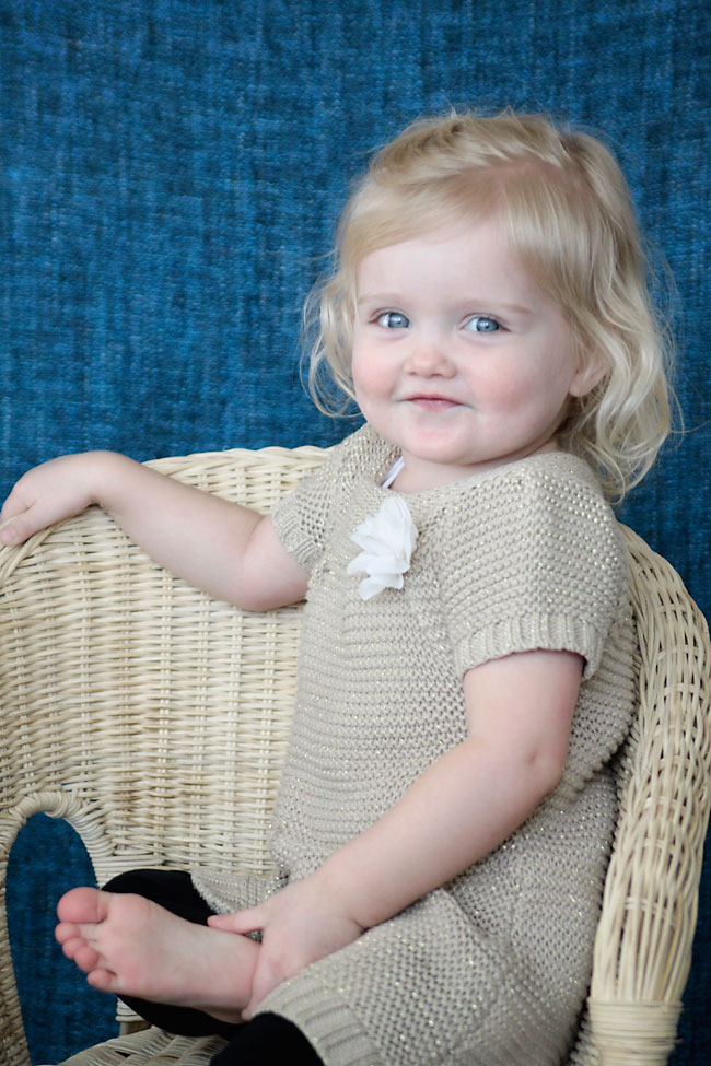 A little girl in a wicker chair smiling