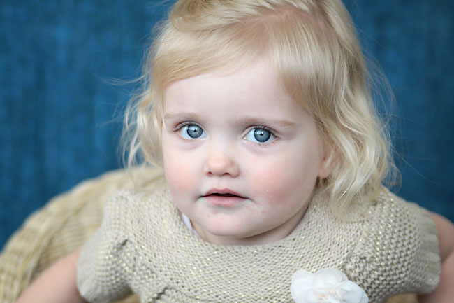 A little girl sitting on a chair in front of a blue blanket