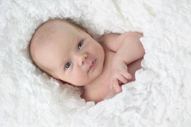 A baby wrapped up in a textured white blanket