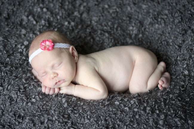 A newborn baby asleep on a grey blanket