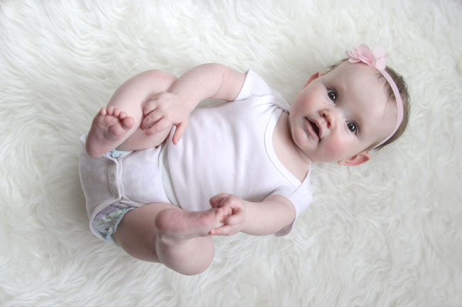 A baby girl on a soft white rug