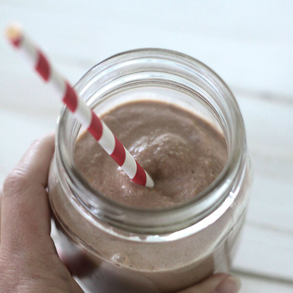 chocolate peanut butter smoothie in a jar with a red and white straw