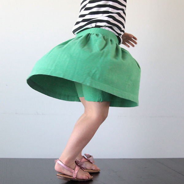 A young girl spinning around wearing shorts that have a skirt attached
