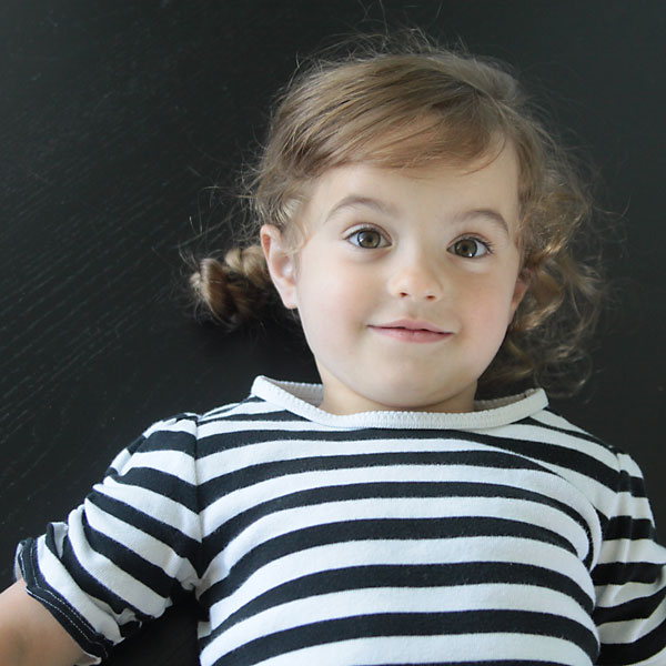 A little girl wearing a striped shirt with ruched sleeves