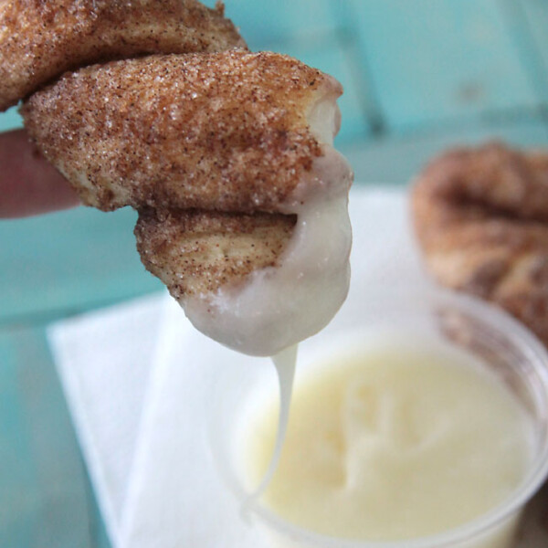 Cinnamon sugar breadstick being dipped in frosting