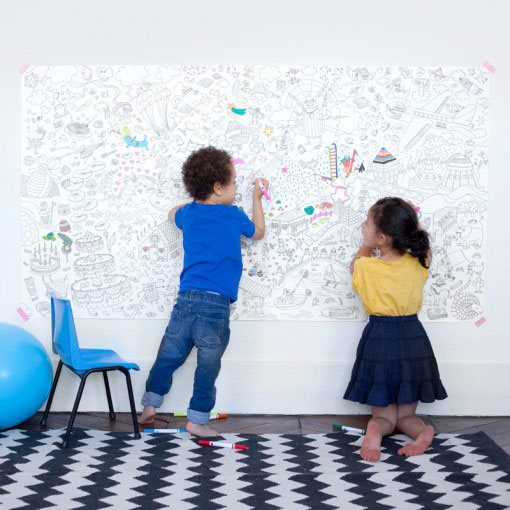 Kids coloring on giant print hung on the wall