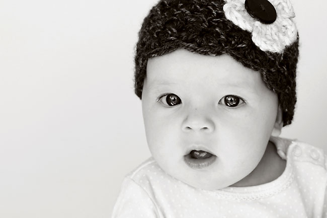 A close up of a baby with a hat in black and white