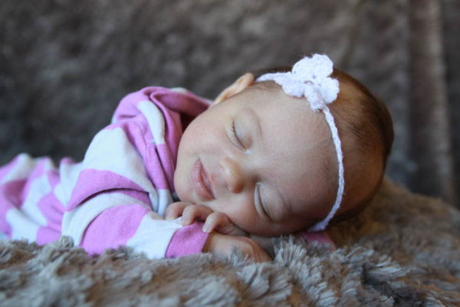 A little girl baby asleep on a blanket with her head on her hands