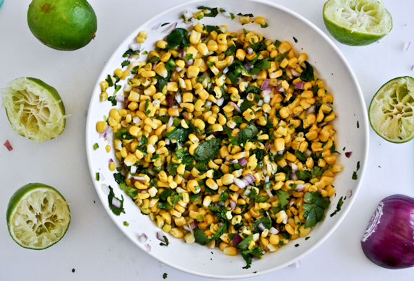 corn salsa in a bowl with limes around it