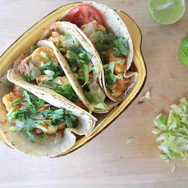 chicken tacos in a dish on a table with garnishes