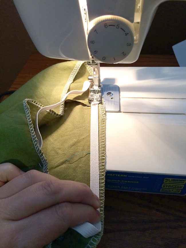Sewing the elastic into the top of the bloomers on a sewing machine, elastic stretched to fit