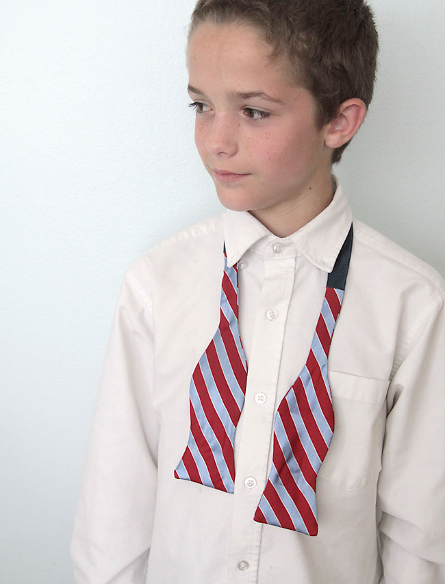A boy with an untied bowtie hanging around his neck