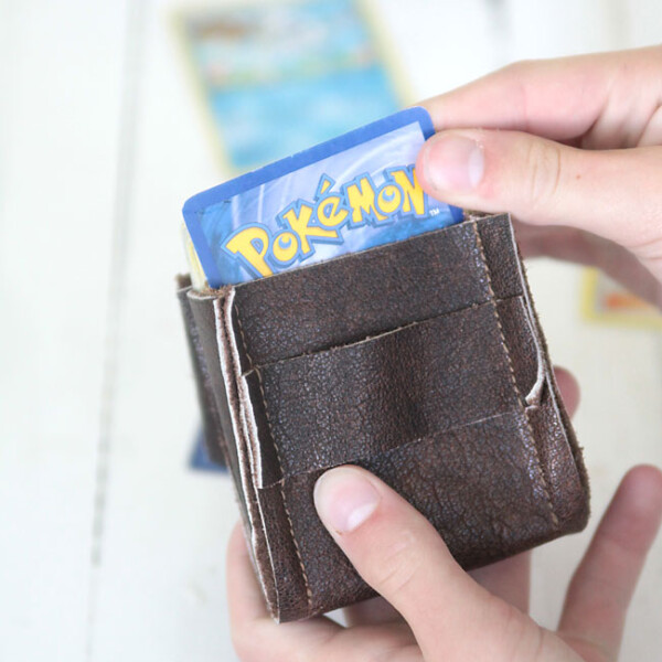 a boy holding a leather deck holder with pokemon cards in it