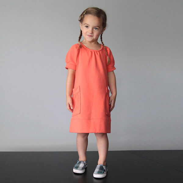 A little girl in an orange dress made from sweatshirt fabric