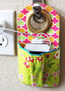 fabric phone charger that hangs on a hook near an outlet with pocket for a phone