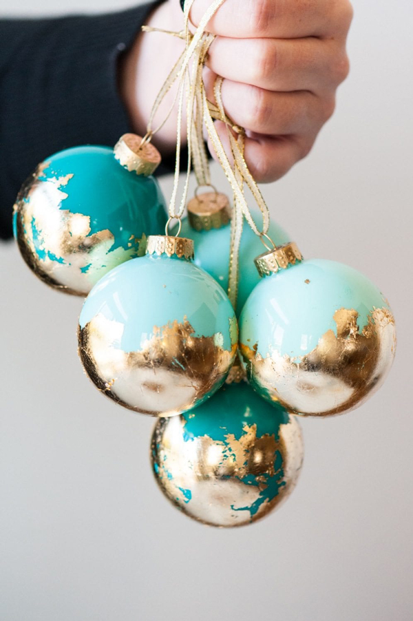 Hand holdings DIY Christmas ball ornaments with gold leaf