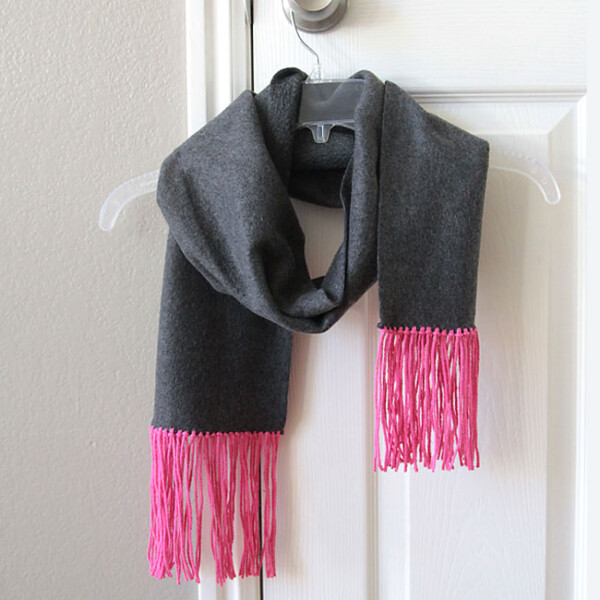 a fleece scarf with yarn fringe hanging on a hanger