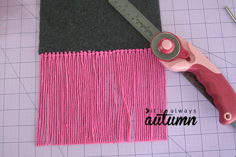 a piece of grey fleece with pink yarn fringe along the short end, rule and trimmer
