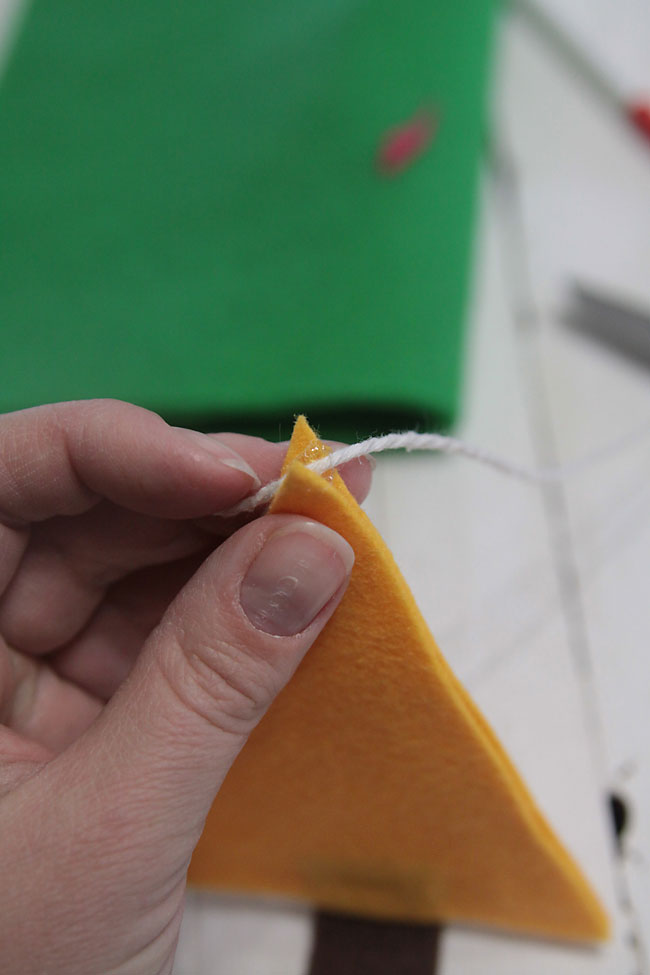 gluing string through tip of felt christmas tree