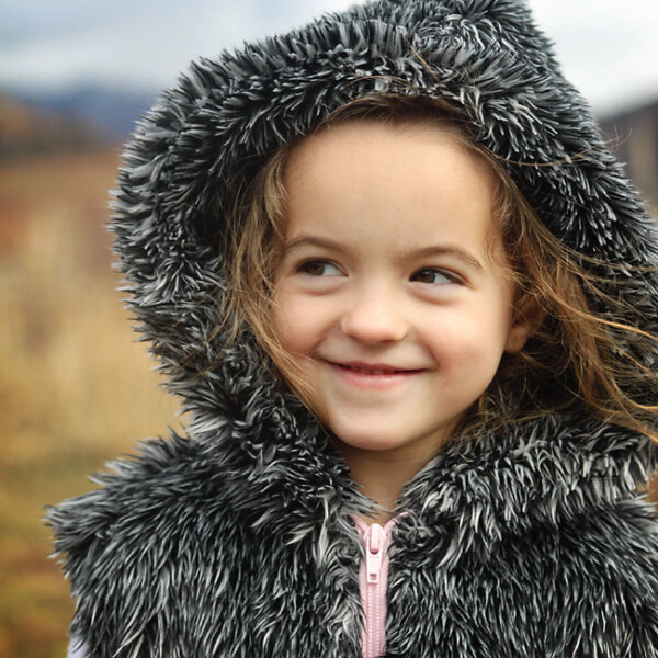 little girl wearing a hooded vest made from faux fur