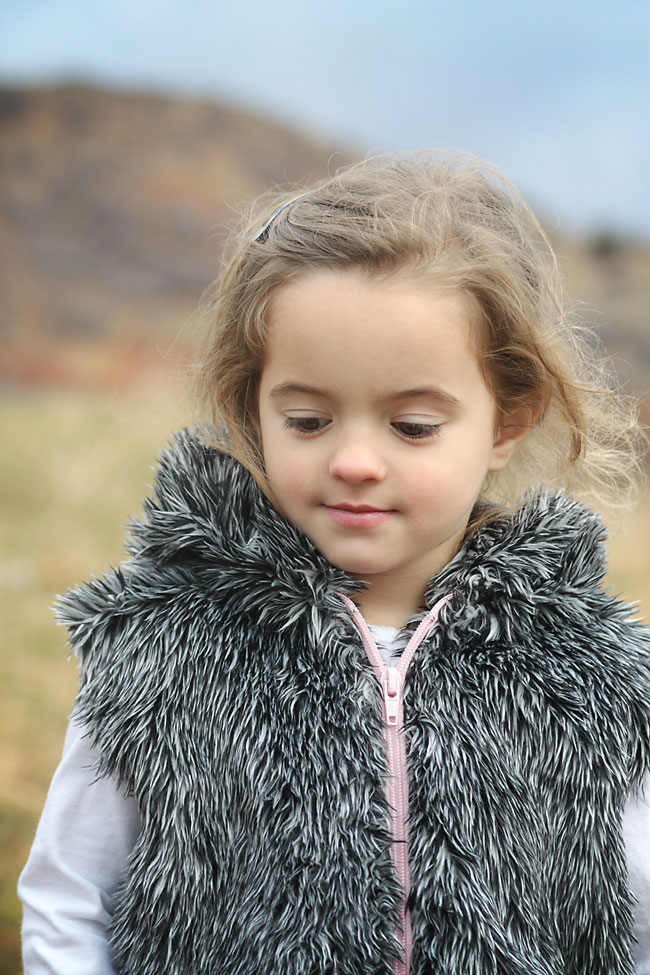A close up of a girl wearing a faux fur vest