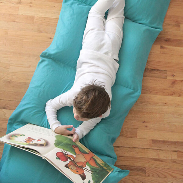 Boy laying on a pillow bed (portable mattress made from five pillows sewn together)