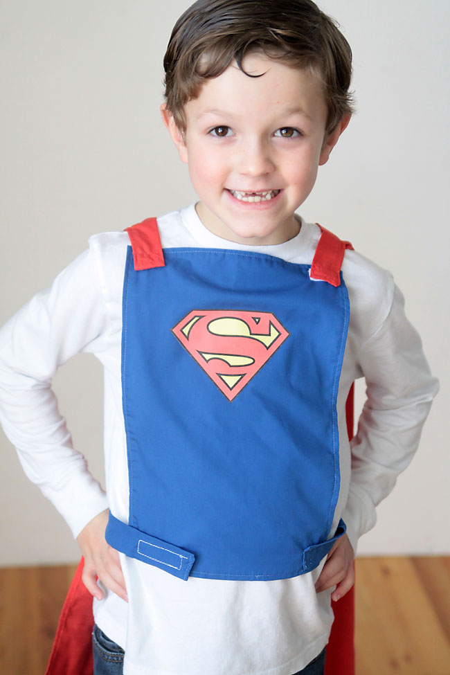 A little boy wearing a blue superhero cape