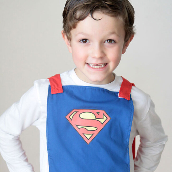 A little boy wearing a blue cape made with elastic so it will easily detach if pulled