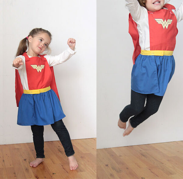 A little girl wearing a superhero cape and skirt