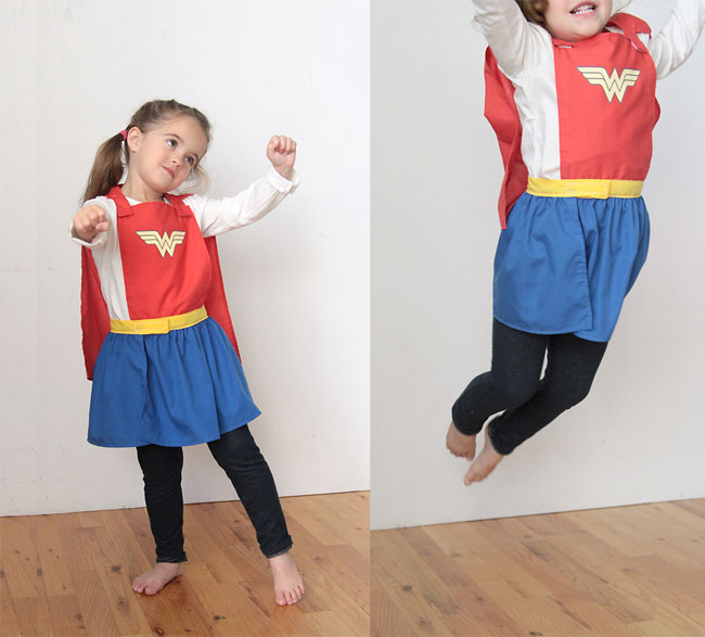 A little girl wearing a superhero cape and skirt