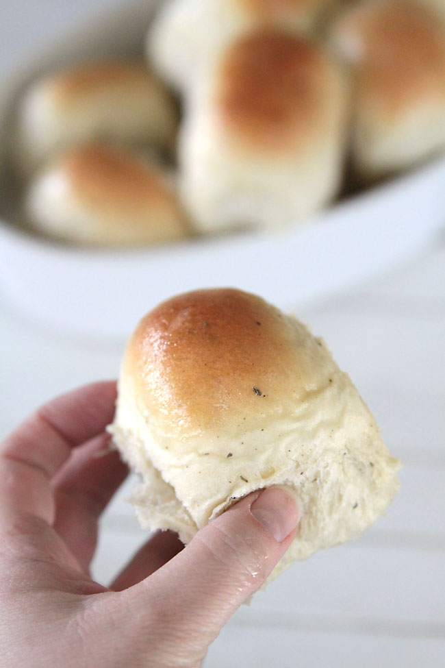 Hand holding a homemade garlic herb dinner roll