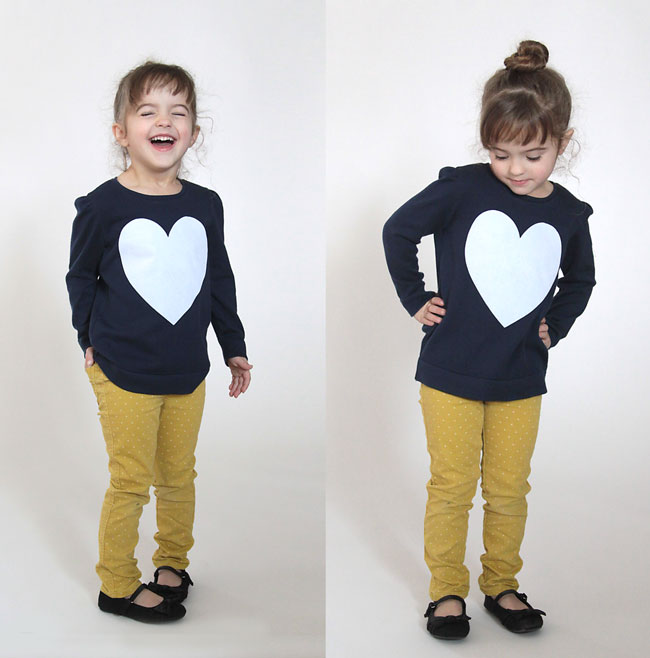 A girl wearing a blue sweater with a big white heart