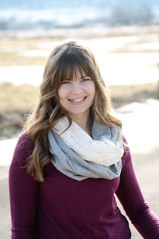 A woman smiling for the camera wearing a scarf made of gray knit and white lace